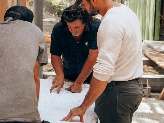 a group of men standing around a white sheet of paper